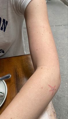 a woman with a tattoo on her arm sitting at a table in front of a plate of food