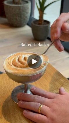 a person holding a spoon over a cup filled with liquid