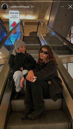 two people sitting on an escalator with their arms around each other