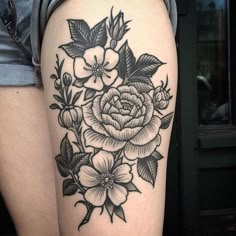 a woman's thigh with black and white tattoos on it, showing flowers in the center