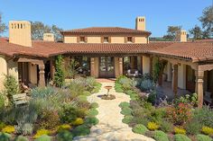 a house with lots of plants in the front yard and walkway leading up to it