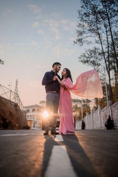 a man and woman standing in the middle of an empty street with their arms around each other