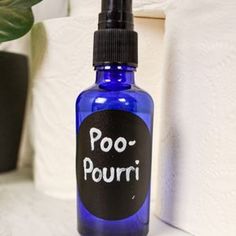 a blue bottle with the word poo - pourri written on it next to a potted plant