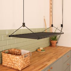 a kitchen with a wooden counter top and green tiles on the wall, hanging from hooks