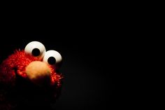 a red stuffed animal with big eyes in the dark