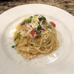 a white plate topped with pasta covered in sauce and cheese on top of a marble counter