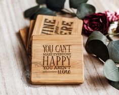 two wooden coasters sitting on top of a table next to flowers and greenery