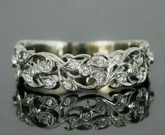 two wedding bands with diamonds on each side and an intricate design in the middle, sitting next to each other