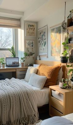 a bedroom with a bed, desk and plants in the window sill on the wall