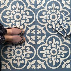 a woman standing on top of a blue and white floor next to a pair of shoes