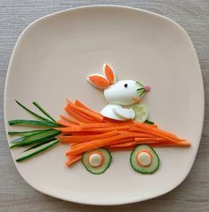 a white plate topped with carrots and cucumber cut into the shape of a bunny