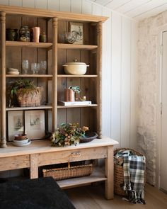 a wooden shelf with plants and dishes on it