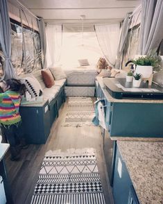 the interior of a camper with blue cabinets and white walls, wood flooring and patterned rugs