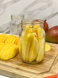 sliced mangoes in a glass jar on a cutting board next to other fruits and vegetables