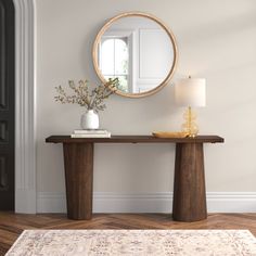 a wooden table with a mirror and vase on it in front of a white door