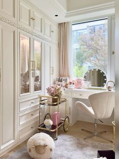 a bedroom with white furniture and pink flowers in the window sill, along with a large mirror