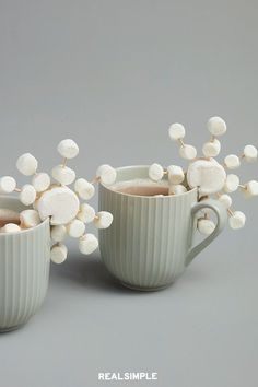 two mugs filled with hot chocolate and marshmallows on a gray background