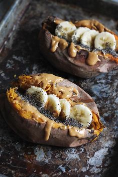 two pieces of bread with bananas and peanut butter on them sitting on a baking sheet