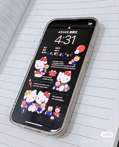 an open notebook with hello kitty stickers on it and a cell phone in the background