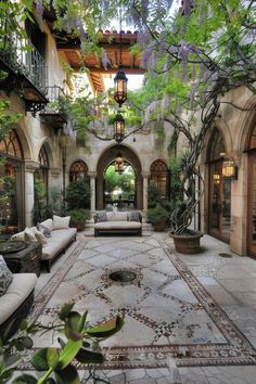 an outdoor living area with couches, tables and potted plants on the floor