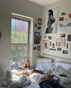 a person laying on top of a bed in a bedroom next to a large window