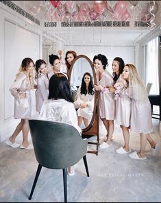 a group of women standing in front of a mirror with balloons hanging from the ceiling