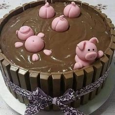 a chocolate cake decorated with pink pigs in the center and brown icing on top