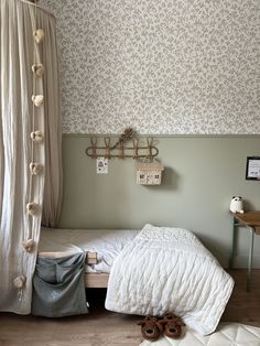 a bedroom with a bed and stuffed animals on the floor in front of a curtain