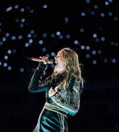 a woman singing into a microphone on stage