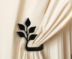 a curtain with a black flower on it hanging from the side of a white wall