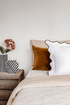 a bed with white sheets and brown pillows