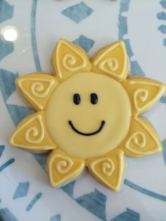 a decorated cookie with a smiley face on it's side sitting on a blue and white plate