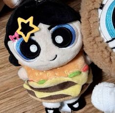 two stuffed animals are sitting next to each other on a wooden floor and one is eating a hamburger