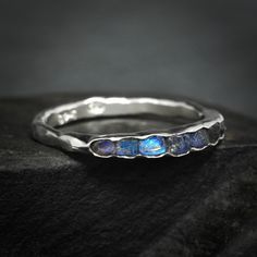 "Raw Uncut Rainbow Moonstone Band Ring // Silver Gold Raw Rough Uncut Organic Rustic Blue Flash Unique Rainbow Moonstone Wedding Band Ring This listing is for one raw natural Rainbow Moonstone band stone ring. Pictured ring is in sterling silver with dark base. DETAILS:  Stone: natural raw Rainbow Moonstone, dark metal base Metal:  - 925 silver  - 925 oxidise black (will start wearing lighter/off immediately) - 14k yellow, rose and white gold - 18k yellow gold Band width: approx. 2x1mm, hammered Fusion Style Moonstone Jewelry For Anniversary, Fusion Style Moonstone Gemstone Ring For Anniversary, Fusion Style Anniversary Moonstone Gemstone Ring, Blue Moonstone Promise Ring, Anniversary Fusion Style Moonstone Gemstone Ring, Wedding Sapphire Ring With Stones In Silver, Anniversary Fusion Style Moonstone Ring, Wedding Sapphire Ring In Silver, Silver Fusion Moonstone Ring For Wedding