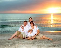 a family poses on the beach at sunset