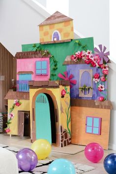 an indoor play house with balloons and flowers on the wall, in front of it