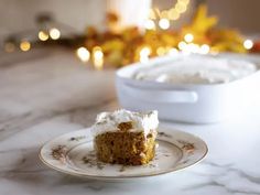 a piece of cake sitting on top of a white plate next to a bowl filled with frosting