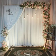 a wedding ceremony with flowers and greenery on the stage, decorated with white drapes