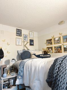 a bedroom with pictures on the wall and a bed covered in blue blankets is shown