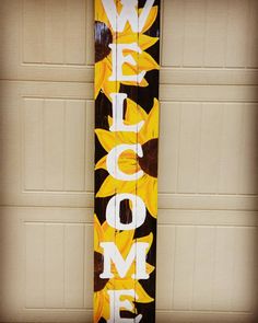 a wooden sign with sunflowers painted on it in front of a garage door