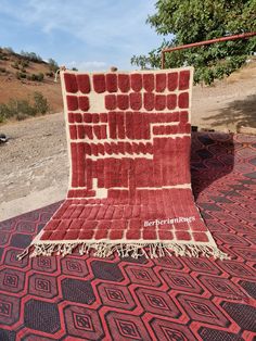 a red and white rug on the ground with a blue sky in the back ground