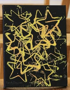 a black and yellow painting sitting on top of a wooden chair