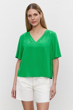 The model is wearing a Velvet by Graham & Spencer JAYCEE SPLIT NECK BLOUSE in woven challis fabric. Flowy V-neck Top For Work, Green Relaxed Fit V-neck Blouse, Chic V-neck Top In Relaxed Fit For Spring, Chic Relaxed Fit V-neck Top For Spring, Chic Relaxed Fit V-neck Top For Summer, Versatile V-neck Viscose Blouse, Versatile Summer Top With Split Neck, Summer Split Neck Top For Day Out, Versatile Split Neck Top For Summer