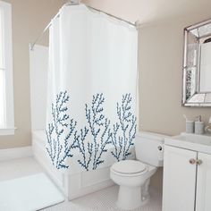 a bathroom with a shower, toilet and sink is shown in this image the curtain has blue corals on it