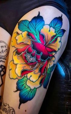 two colorful tattoos on the thighs of women's legs, one with flowers and leaves