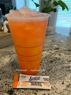 an orange drink sitting on top of a counter next to a bar with some ice