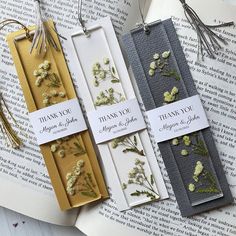 three bookmarks with flowers on them sitting on top of an open book