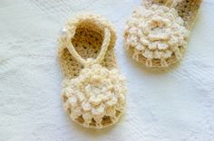 two crocheted baby shoes sitting on top of a white blanket next to each other