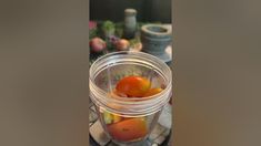 a glass jar filled with oranges on top of a table