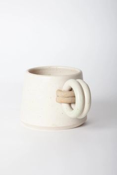 a white ceramic cup with a knot on the side and two wooden sticks sticking out of it